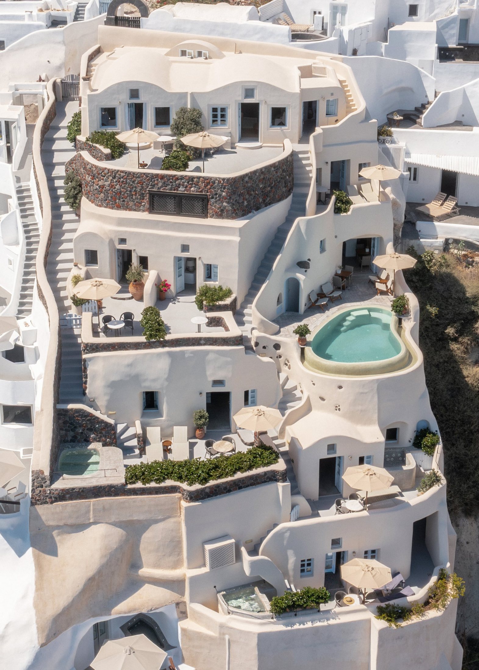 Plastered terraces, stairs and a pool on a hillside, seen from above.